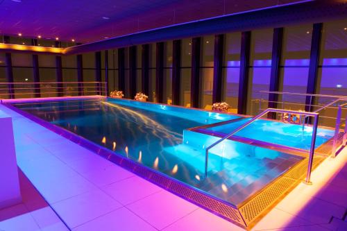 莱顿Fletcher Wellness-Hotel Leiden的一座紫色照明建筑中的大型游泳池