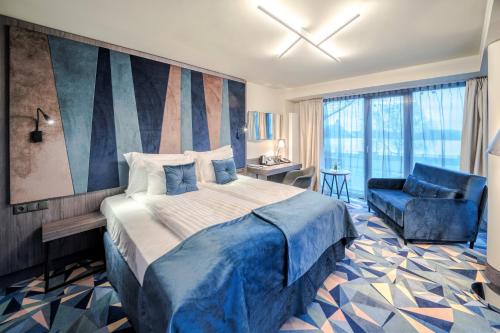 里加Wellton Riverside SPA Hotel的一间卧室配有一张大床和一张蓝色椅子