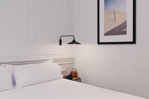 瓦伦西亚Helen Berger Boutique Hotel的白色的床、白色枕头和黑色灯
