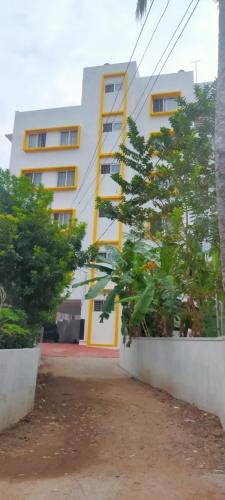 特里凡得琅Nachiyar Suites的一座黄色和白色的建筑,前面有树木