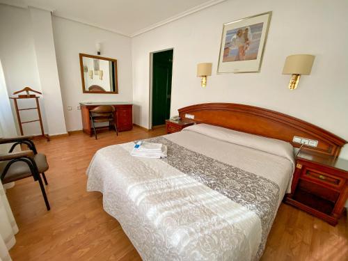 阿尔巴塞特卡迪纳尔酒店的卧室配有1张床、1张桌子和1把椅子
