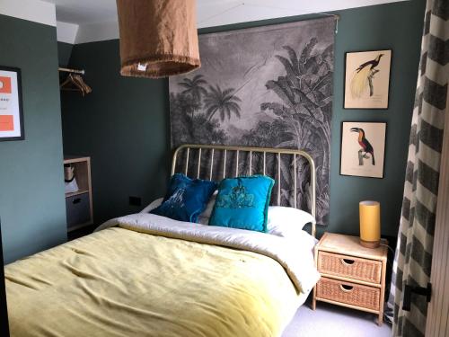 奇切斯特Boutique home near Chichester centre的一间卧室设有绿色的墙壁和一张带蓝色枕头的床。