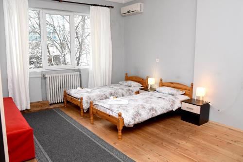 索非亚Santa Sofia的配有红色沙发和窗户的客房内的两张床