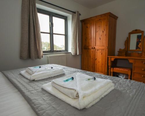 康威Conwy Valley Hotel Cottages的卧室配有带2条毛巾的窗户,位于床上