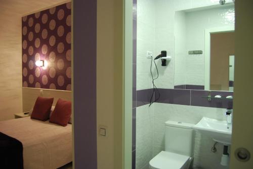 马德里Hostal PETITE MAMAN的浴室设有床、卫生间和水槽。