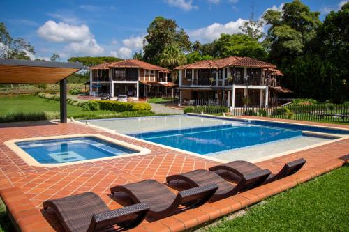金巴亚Finca Hotel Casa Nostra, villa Mariana的一个带两把椅子的游泳池以及一座房子