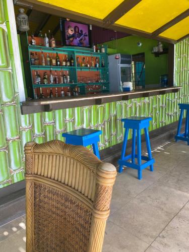 Crab HillOrrie's Beach Bar and Hotel的酒吧前的藤椅,带蓝色凳子