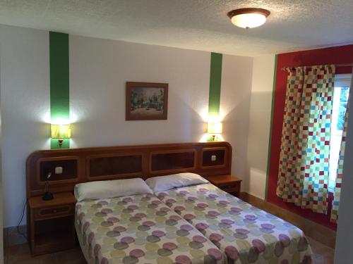 Los QuemadosApartamentos colon y bungalows的一间卧室配有一张大床,两盏灯