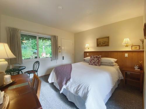安吉利斯港Emerald Valley Inn的一间卧室配有一张床、一张书桌和一个窗户。