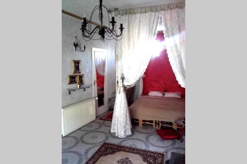 科马罗姆Romantic Studio Apartment in the heart of the city的一间卧室配有一张粉红色墙壁和吊灯的床。