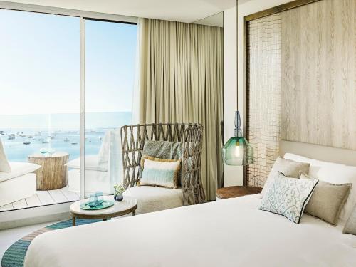 塔拉曼卡伊比沙湾诺布酒店的一间卧室配有一张床、一把椅子和一个大窗户