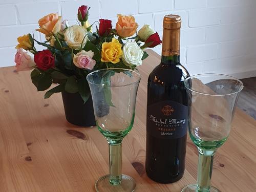 卡尔斯特Charmant und stilvoll的一瓶葡萄酒和两杯带鲜花的桌子