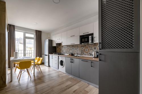 利沃夫City Aparts Kulisha Str的厨房配有白色橱柜和桌椅