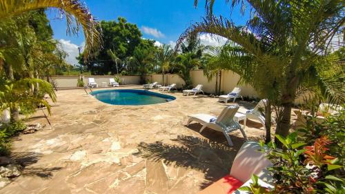 桑给巴尔Golden Palm Boutique Zanzibar的后院设有游泳池、椅子和棕榈树