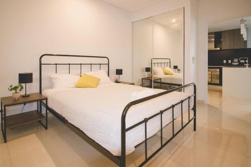 达尔文ZEN CENTRAL CBD - Affordable 3-Bdrm Apt in the Heart of Darwin City的一间卧室配有一张床、一张桌子和一面镜子