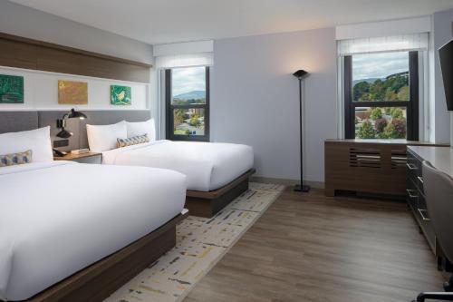查塔努加Hotel Indigo Chattanooga - Downtown, an IHG Hotel的一间卧室配有两张床、一张桌子和两个窗户。
