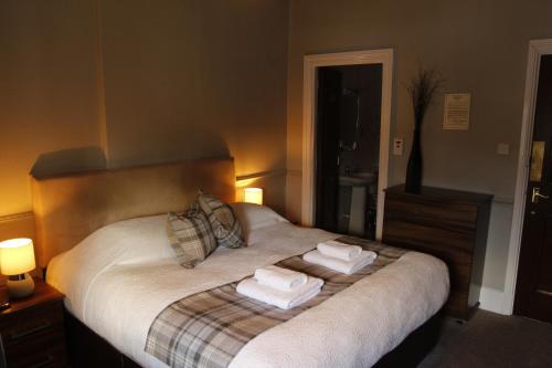 鲍内斯温德米尔皇家橡树旅馆的一间卧室配有一张床,上面有两条毛巾