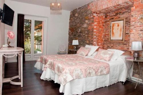 桑坦德秘密花园旅馆的一间卧室设有一张床和砖墙