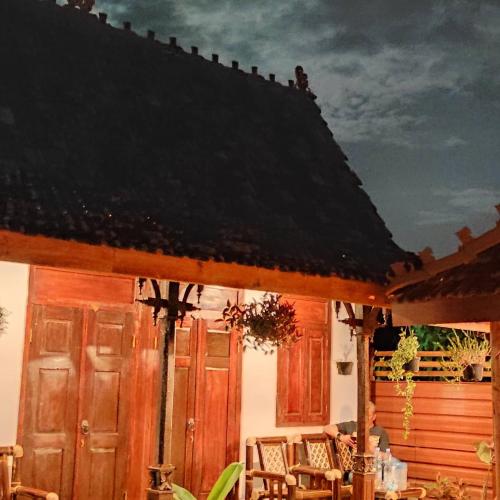 日惹Omah Kampong的庭院中设有木门和椅子的房子