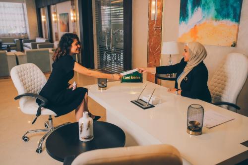 开罗Jewel Green Mountain Hotel的两个坐在桌子边读书的女人