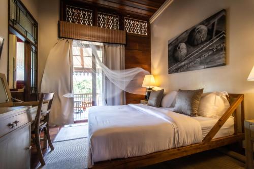 尖竹汶Punyashthiti villa的一间卧室配有一张床、一张书桌和一个窗户。