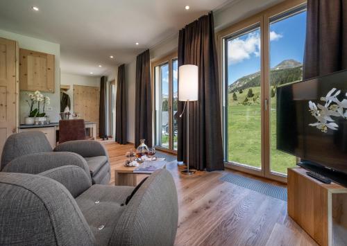 阿罗萨高尔夫球－&霍夫马朗运动酒店的带沙发、电视和大窗户的客厅