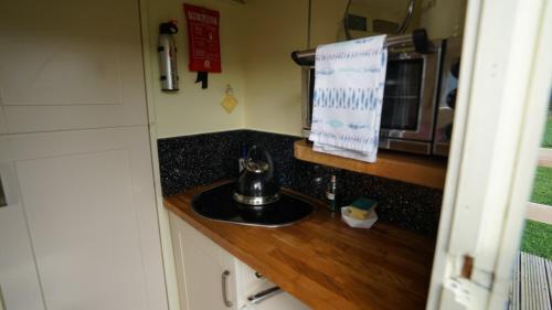 霍伊克Showman's Hut Westcote的厨房柜台设有水槽和微波炉