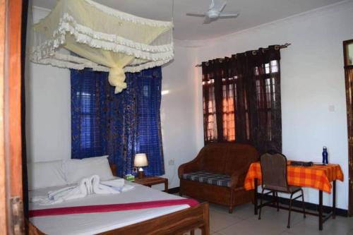 BunjuRemarkable 10-Bed Cottages in Bagamoyo的一间卧室配有一张床、一把椅子和一张书桌