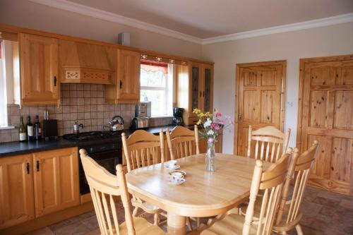 GrangeInviting 4-Bed House in Strokestown的厨房配有木桌、椅子、桌子和桌子