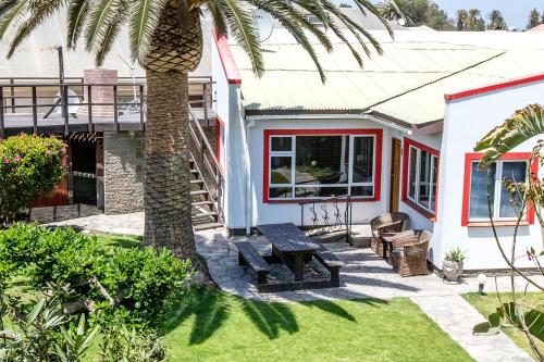 鲸湾港Stay Cleverly Self Catering Apartments的棕榈树和长凳的房子