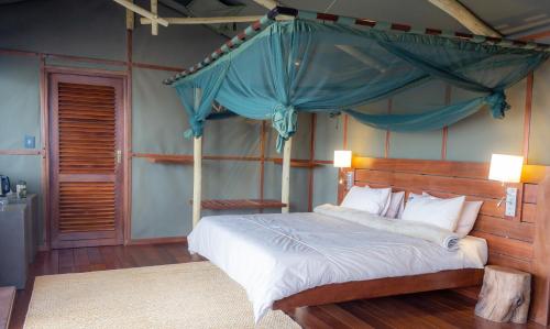 Mahango努霍夫野生动物山林小屋的一间卧室配有一张带天蓬的床