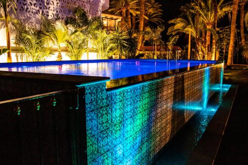 马斯帕洛马斯Eden Meloneras by TAM Resorts的夜晚的游泳池拥有蓝色和绿色的灯光