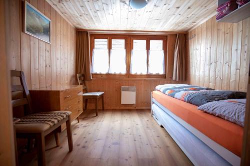 雷金根Alpensonne的一间卧室配有一张床、一张书桌和一个窗户。