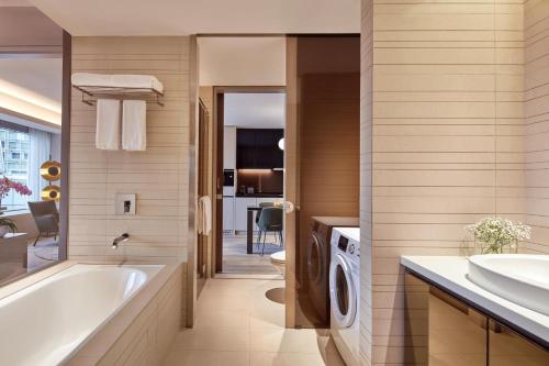 新加坡Pan Pacific Serviced Suites Orchard, Singapore的带浴缸、水槽和洗衣机的浴室