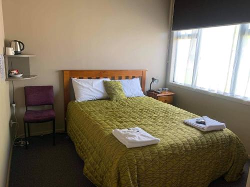 OwakaCatlins Inn的一间卧室配有一张床,上面有两条毛巾