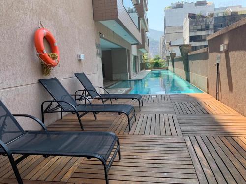 里约热内卢Arpoador Premium Suítes的大楼内带椅子的甲板和游泳池