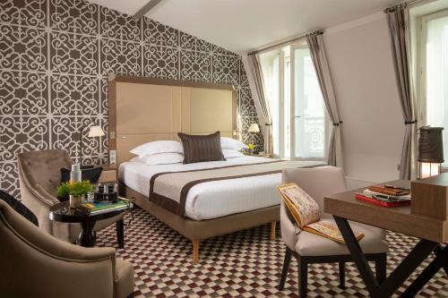巴黎Philéas Lazare & Spa的酒店客房带一张床、一张桌子和椅子