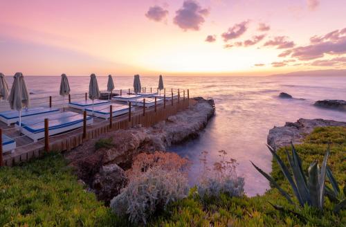 赫索尼索斯星湾乡村&水上公园酒店的日落时分带遮阳伞和海洋的码头