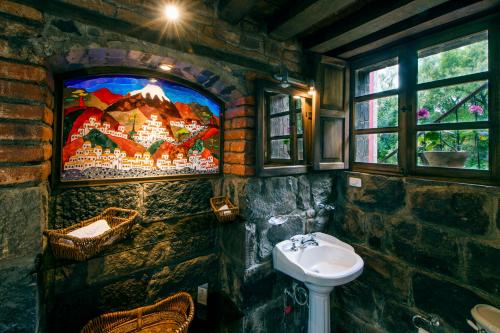 Mulaló哈托维德庄园酒店的石质浴室设有水槽,墙上配有电视。