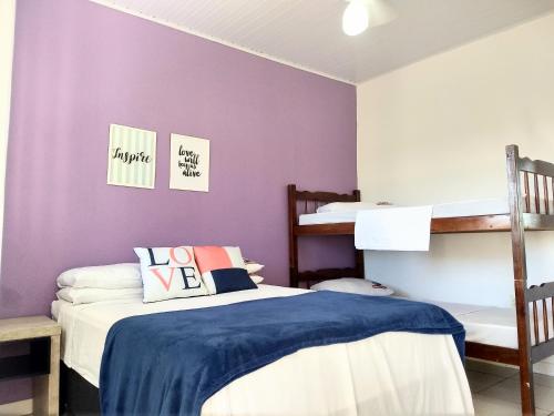 特拉曼达伊Pousada No Farol的一间卧室设有两张双层床和紫色墙壁。