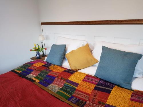 ThreshfieldThe Sett on The Wharfe的床上有色彩缤纷的毯子和枕头