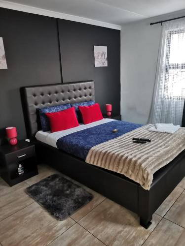 开普敦ILITHA PARK的一间卧室配有一张带红色枕头的大床