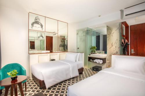 暹粒UTEY Hotel的酒店客房设有两张床和一张桌子。