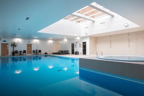 泰姆The Oxfordshire Golf & Spa Hotel的一座大楼内一座带浴缸的大型游泳池