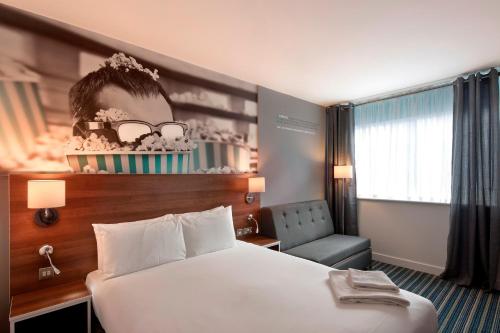 利物浦Heeton Concept Hotel - City Centre Liverpool的配有一张床和一把椅子的酒店客房