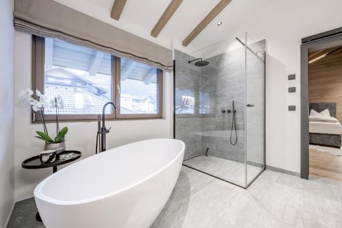 朗根费尔德Alpenchalet Tirol的白色的浴室设有浴缸和淋浴。
