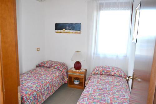 莫诺波利2 bedrooms house at Monopoli 100 m away from the beach with sea view enclosed garden and wifi的一间卧室配有两张床和一张带台灯的桌子