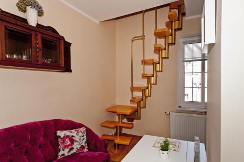 格但斯克Poddasze na Piwnej的一间带红色沙发的客厅和螺旋楼梯