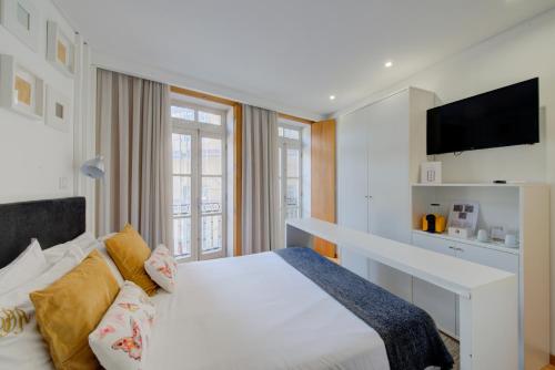 吉马良斯Bellu Suites的卧室配有白色的床和电视
