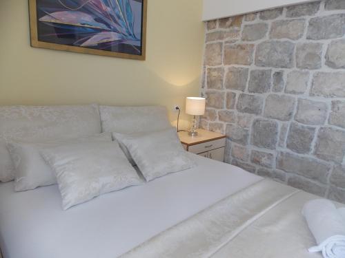 斯普利特华伦天奴酒店的卧室配有白色的床和石墙